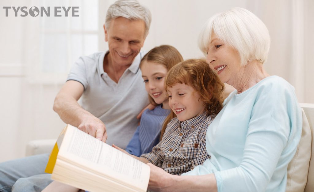 Two adults reading to two children after saying goodbye to glasses after cataract surgery with UV adjustable IOLs
