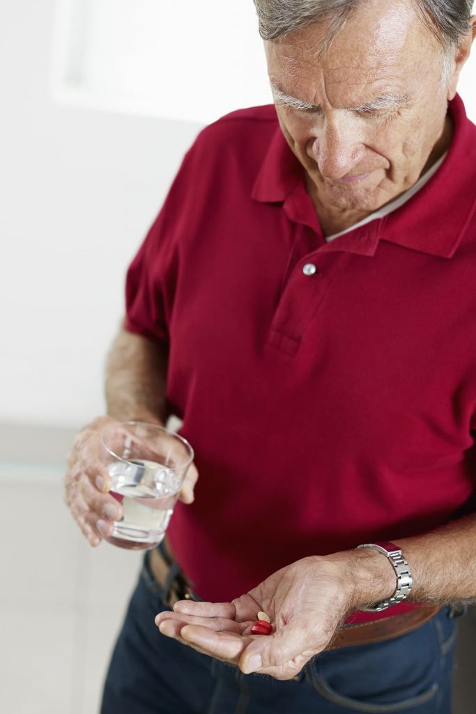 A senior man taking medication before a cataract surgery
