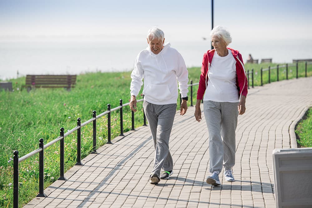 A senior man and woman taking a walk through a park