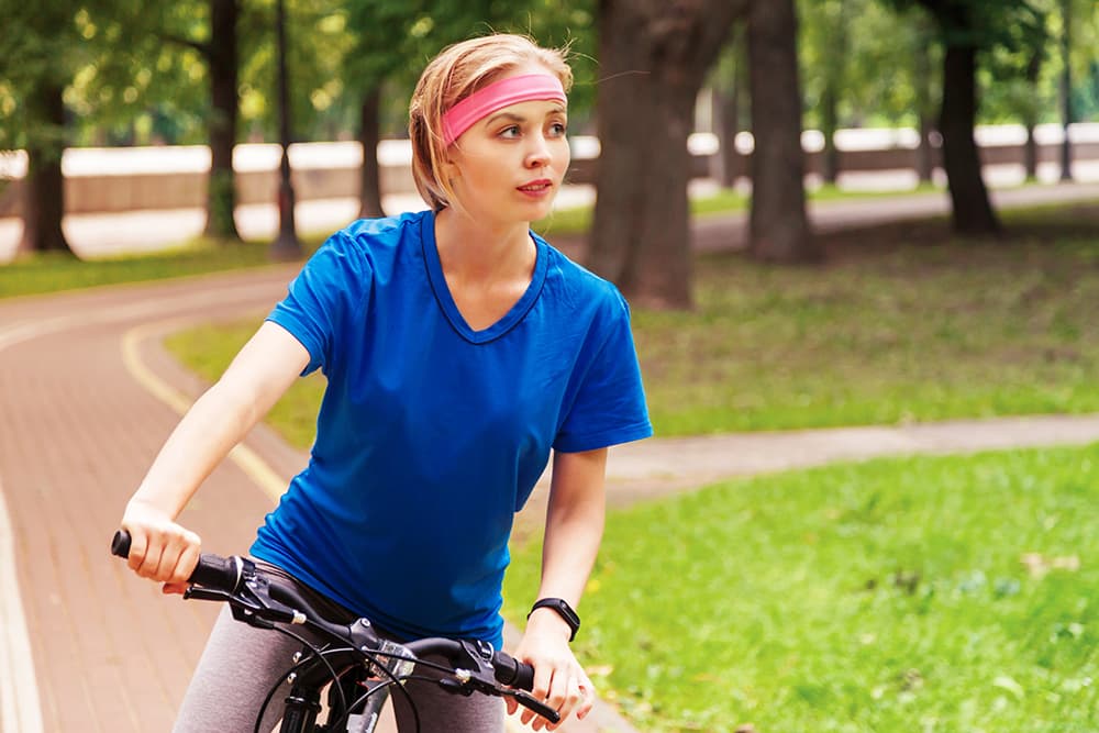 A young woman riding on a bike through a park