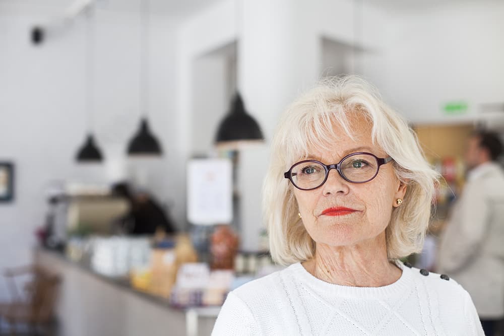 Senior woman with glasses standing confidently