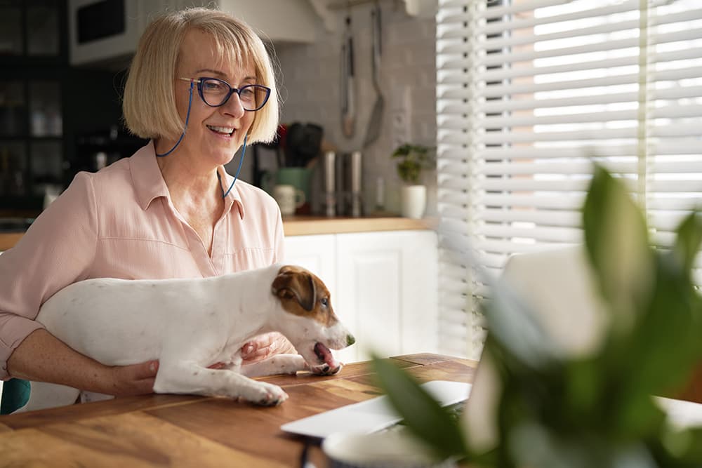 Senior woman with glasses sitting at the table with her dog