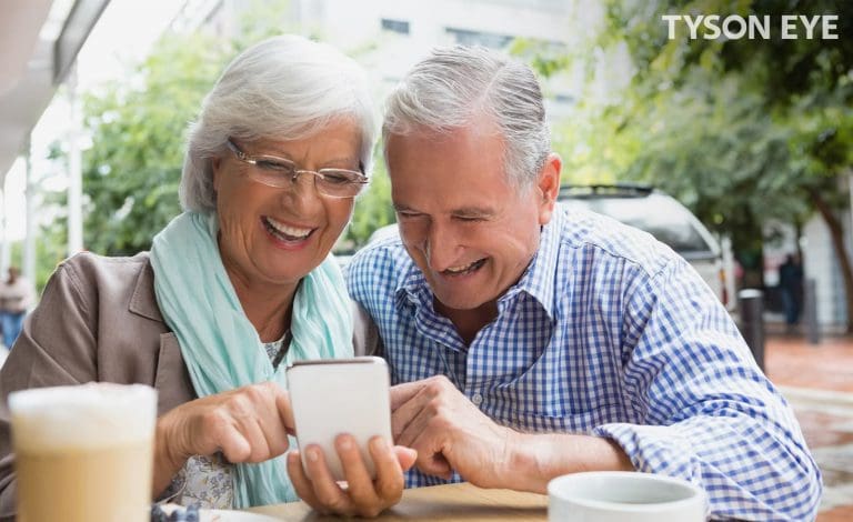 Two people looking at a phone smiling and understanding why you should change your perscription glasses