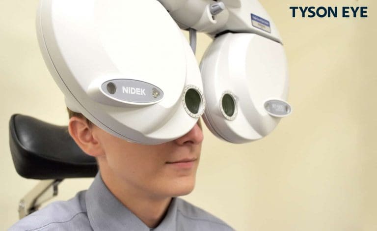 someone looking through an eye exam machine to show what the refraction test is and why it is needed